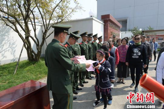 武警战士们给孩子们发放国防知识传单。　刘威 摄