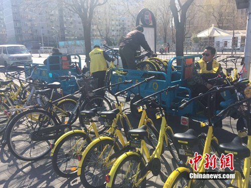 某家共享单车企业运维人员正将故障车放进三轮车内，集中收回。中新网 吴涛 摄